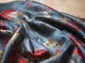 Tissu de soie bleu nuit avec un motif de fleurs rouges et de feuilles dorées. Une tache de gras sur soie, subtile, se fond dans le motif.