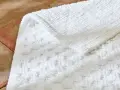 Un tapis de bain blanc moelleux, avec un motif texturé, est posé sur un sol en terre cuite. Il est temps de se demander a combien laver un tapis de bain pour qu'il reste ainsi.