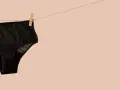 Culotte menstruelle noire en dentelle, suspendue sur une corde à linge. Apprenez comment laver culotte menstruelle pour une utilisation durable.