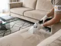Un professionnel utilise un appareil pour nettoyer un canapé beige. Ce **produit maison pour shampouineuse canapé** redonne un coup de neuf à votre mobilier.