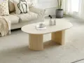 Table basse ovale avec pieds cannelés, sur un tapis doux. Quelle déco avec du travertin, une tasse et des vases sur la table.