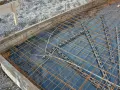 Préparation pour couler une dalle béton : film plastique, treillis métallique et coffrage en bois. On ne coule pas une dalle béton directement sur la terre.