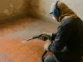 Un ouvrier protégé utilise un appareil pour décaper un carrelage ancien. La poussière s'élève, révélant la beauté sous-jacente.