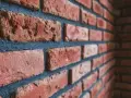 Gros plan sur un mur de briques rouges avec des joints bleus foncés. Idéal pour illustrer comment nettoyer des briques après avoir fait les joints.