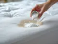 Main blanche, une main verse une poudre blanche sur une tache sur un matelas. Aide à nettoyer matelas pipi.