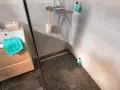 Sol de douche en galets sombres, contrastant avec le carrelage clair des murs. Une paroi vitrée sépare l'espace.
