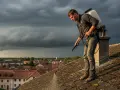 Un homme traite un toit couvert de mousse, sous un ciel orageux. Il se demande combien de temps avant pluie son anti-mousse sera efficace.