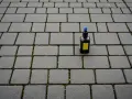 Bouteille de vinaigre blanc sur des pavés autobloquants gris, prête pour un nettoyage écologique.