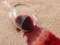 Verre de vin renversé sur la moquette, créant une tache rouge. Une astuce de grand-mère pour une tache de vin rouge serait utile ici.
