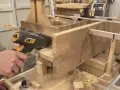 Un artisan utilise un outil pour enlever le saturateur bois d'une pièce de bois massif.
