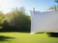 Un oreiller blanc sèche au soleil, suspendu à une corde à linge avec des pinces à linge. Un symbole de fraîcheur et de propreté après un bon nettoyer oreiller.