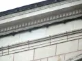 Détail d'une façade en tuffeau avec des câbles noirs fixés. L'image montre comment poncer du tuffeau pour restaurer sa surface.
