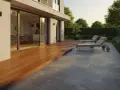 Une terrasse en ardoise naturelle grise, adjacente à une terrasse en bois, avec des chaises longues et un jardin luxuriant.