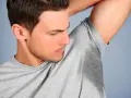 Un homme sent ses aisselles moites, cherchant comment enlever les taches sous les aisselles.