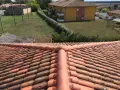 Vue aérienne d'un toit en tuiles rouges, avec des bâtiments et de la verdure en arrière-plan. Faut-il imperméabiliser les tuiles pour les protéger ?
