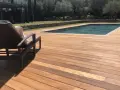 Terrasse en bois d'Ipe, baignée de soleil, avec une chaise longue invitant à la détente près de la piscine.