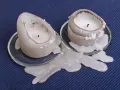 Deux bougies fondent, laissant une tache de bougie sur la pierre poreuse. La cire blanche coule sur les soucoupes en verre.