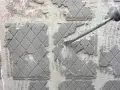 Outil pneumatique en action pour enlever ciment colle sur carrelage. Poussière et débris volent.