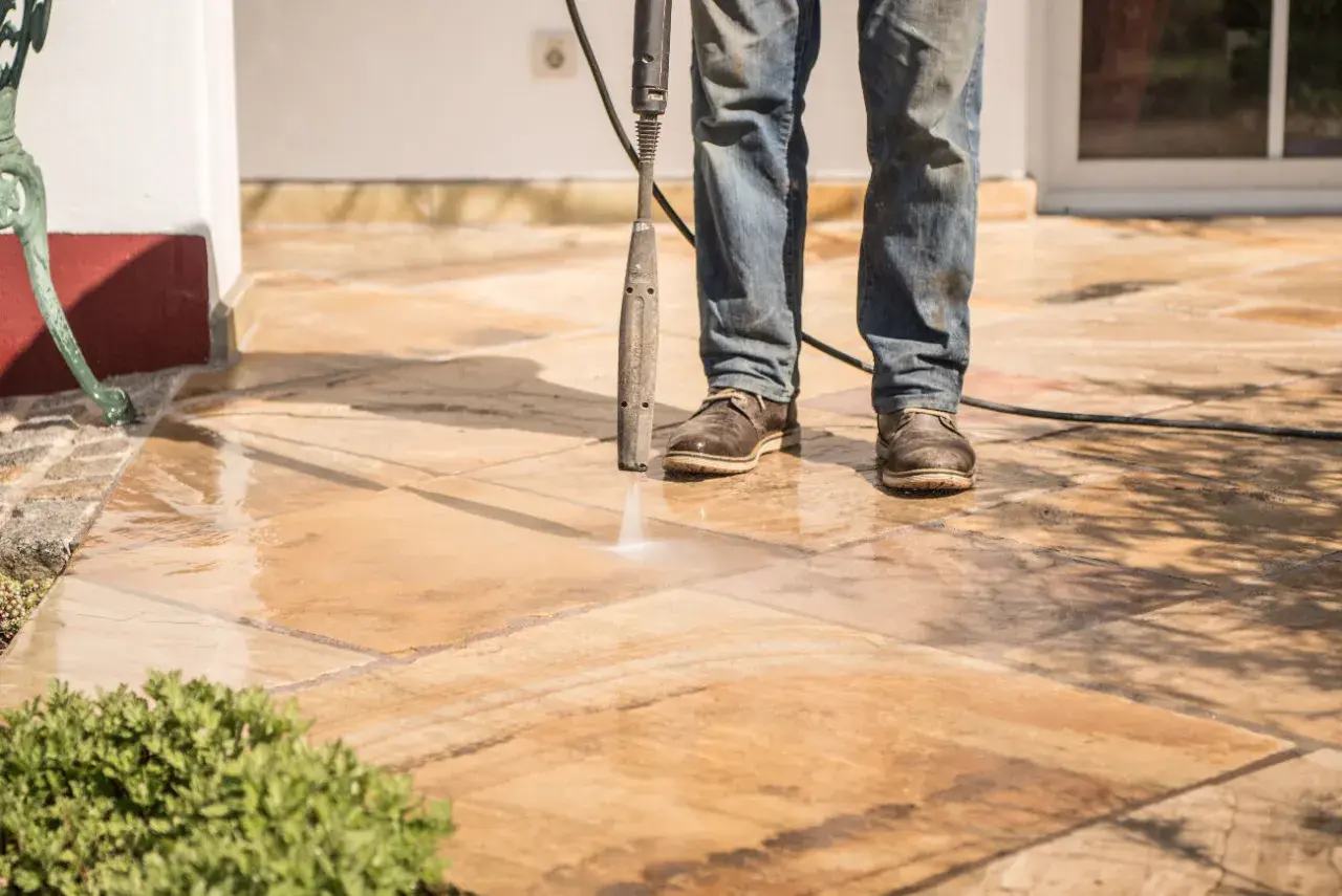 Nettoyer carrelage extérieur noirci avec un nettoyeur haute pression. L'eau projetée révèle la beauté naturelle des dalles.