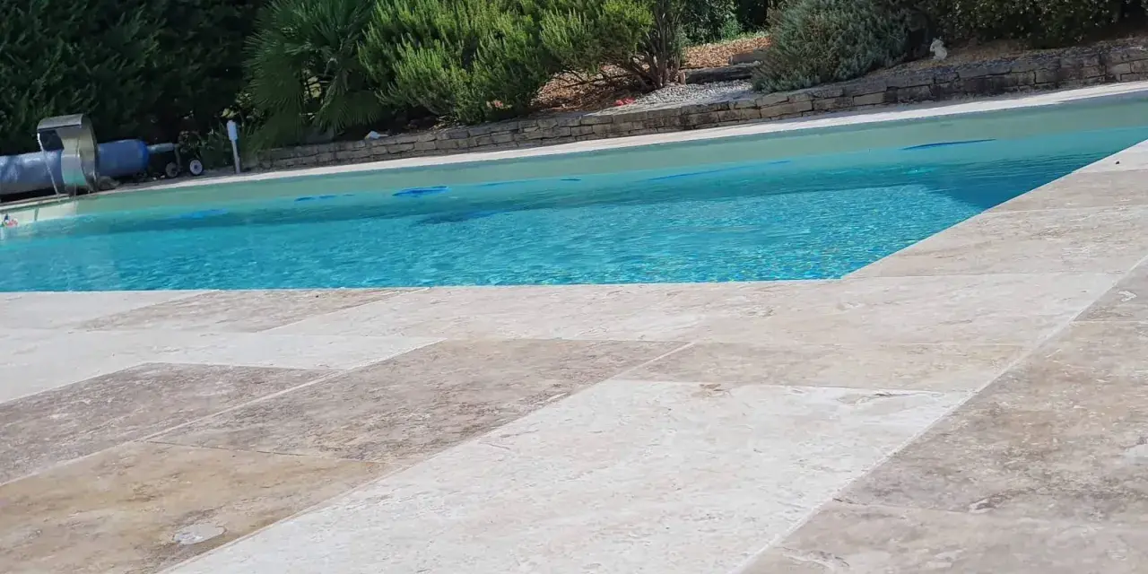 Le travertin autour de la piscine crée une terrasse naturelle et élégante, invitant à la détente sous le soleil.