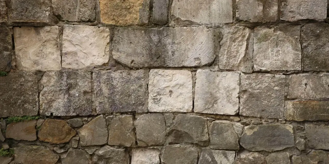 Mur en pierres naturelles, certaines semblant prêtes à décaper pour révéler leur éclat d'origine.