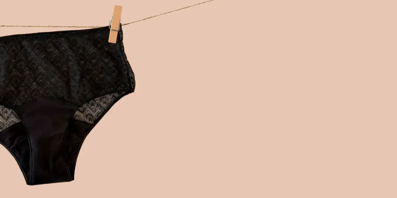 Culotte menstruelle noire en dentelle, suspendue sur une corde à linge. Apprenez comment laver culotte menstruelle pour une utilisation durable.