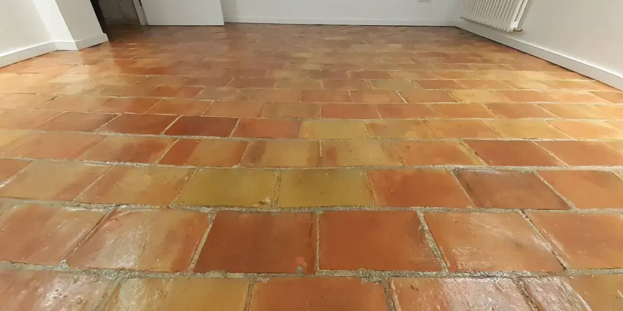 Sol en terre cuite aux tons chauds, avec un joint de barbotine visible entre les carreaux.