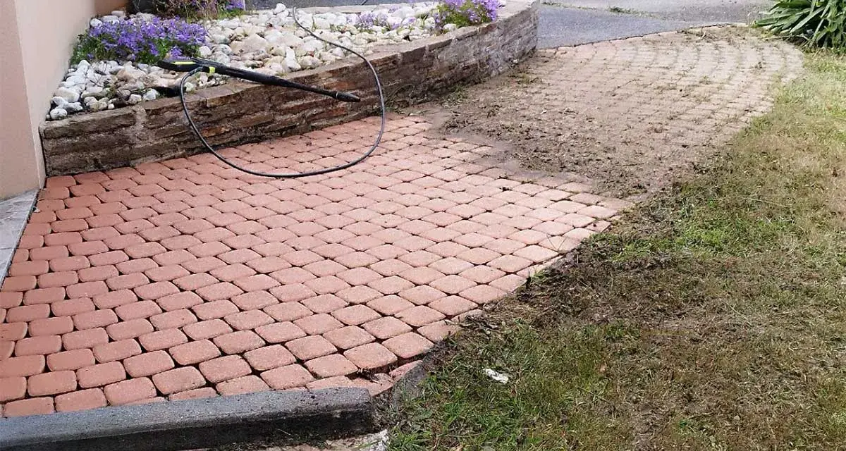 Un nettoyeur haute pression enlève les taches noires, lichen noir sur pierre. Le pavage est presque propre.