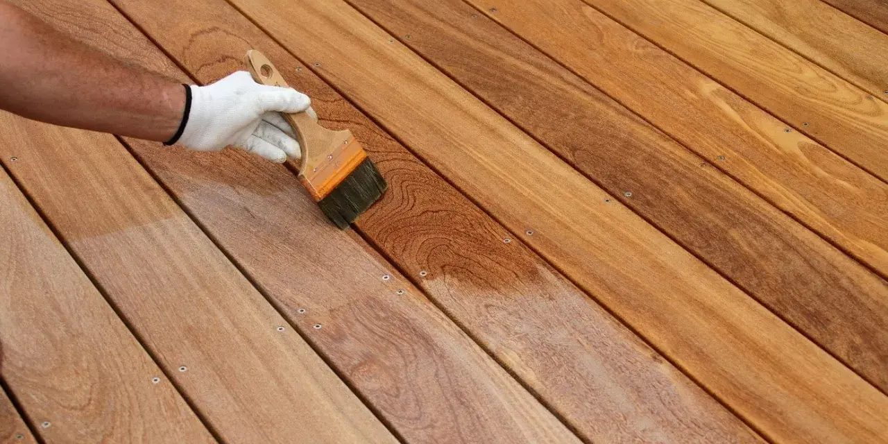 Application d'un produit protecteur sur un platelage en bois exotique, révélant sa beauté naturelle.