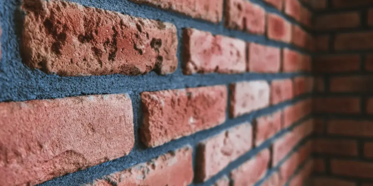 Gros plan sur un mur de briques rouges avec des joints bleus foncés. Idéal pour illustrer comment nettoyer des briques après avoir fait les joints.