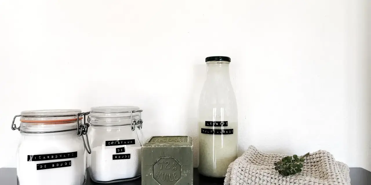 Ingrédients pour la meilleure recette lessive maison : bicarbonate de soude, cristaux de soude, savon de Marseille et une bouteille de lessive liquide.