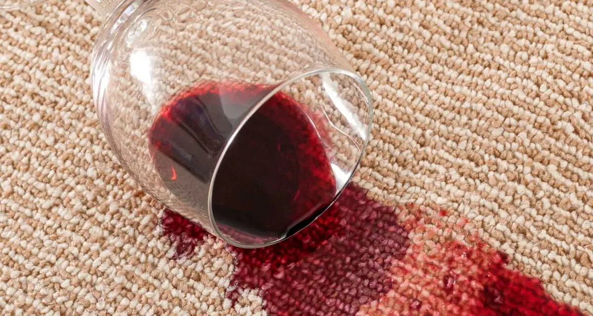 Verre de vin renversé sur la moquette, créant une tache rouge. Une astuce de grand-mère pour une tache de vin rouge serait utile ici.