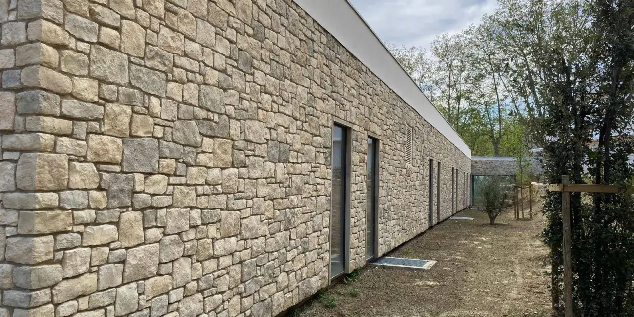 Façade d'un bâtiment moderne avec un revêtement en pierre calcaire construction, créant une esthétique naturelle et robuste.