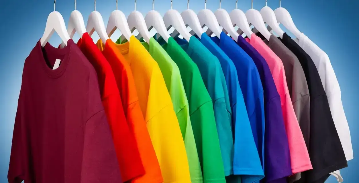 Une rangée de t-shirts colorés sur des cintres blancs, un arc-en-ciel de couleurs pour raviver les couleurs du linge.