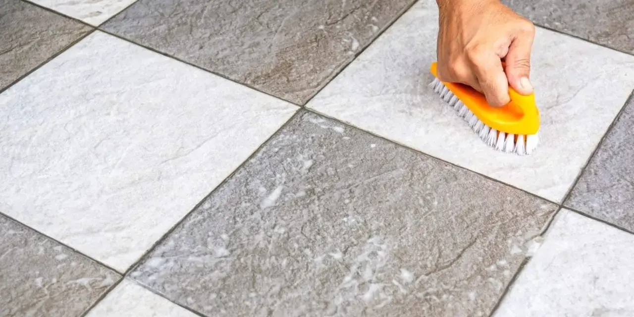 Main tenant utilise une brosse jaune pour faire briller le carrelage, révélant sa beauté naturelle.