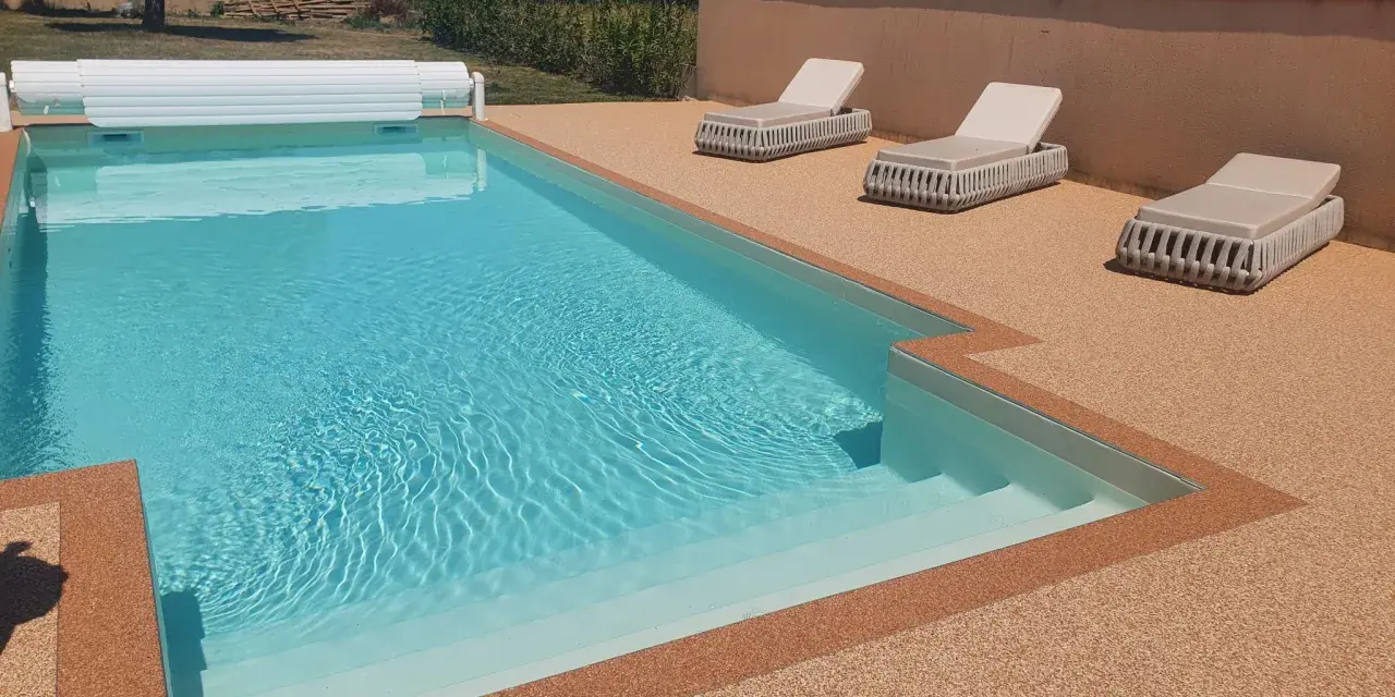 Piscine avec escalier, entourée de **pierre autour piscine** et de chaises longues.