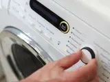 Main d'une personne réglant la température de lavage d'une couette sur un panneau de commande de machine à laver.