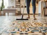 Une personne nettoie des carreaux de ciment anciens avec une brosse.