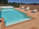 Piscine avec escalier, entourée de **pierre autour piscine** et de chaises longues.