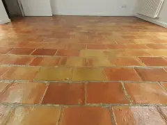Sol en terre cuite aux tons chauds, avec un joint de barbotine visible entre les carreaux.