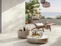 Terrasse avec pose travertin sur carrelage existant. Chaise longue, tables basses et vue mer. Ambiance détente.