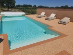 Piscine avec escalier, entourée de **pierre autour piscine** et de chaises longues.