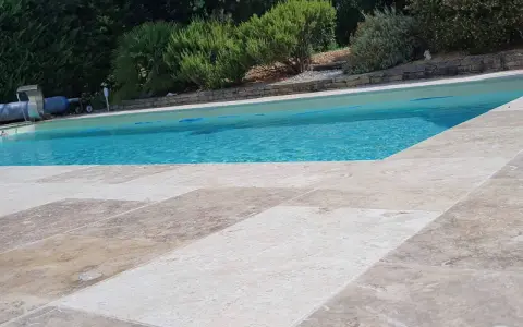 Le travertin autour de la piscine crée une terrasse naturelle et élégante, invitant à la détente sous le soleil.