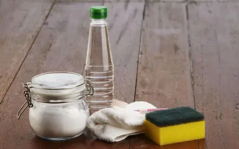Bicarbonate de soude dans un bocal, une bouteille de vinaigre, une éponge et une brosse à dents. Idéal pour 15 utilisations du bicarbonate de soude.
