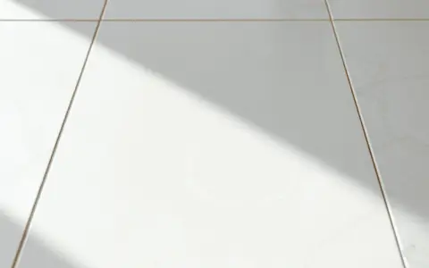 Laitance sur carrelage blanc, une ombre diagonale traverse la scène. Comment enlever laitance carrelage naturellement ?