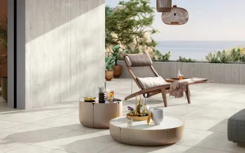 Une **terrasse en travertin** aux tons clairs, avec mobilier de détente et vue mer. Avis : un espace paisible et élégant.