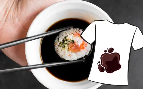 Une main tient une pince à sushi trempant un rouleau dans une sauce soja. Une tache de sauce soja est dessinée sur un t-shirt blanc.