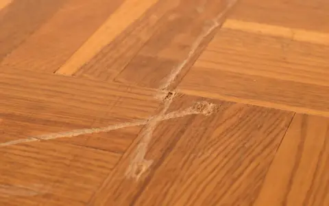 Parquet vitrifié abîmé par des frottements, montrant des marques et des éclats de bois. Comment enlever trace de frottement sur parquet vitrifié.