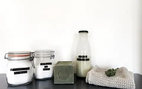 Ingrédients pour la meilleure recette lessive maison : bicarbonate de soude, cristaux de soude, savon de Marseille et une bouteille de lessive liquide.