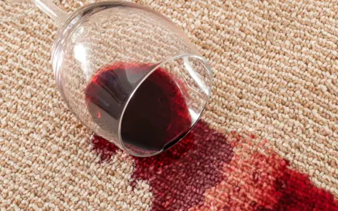 Verre de vin renversé sur la moquette, créant une tache rouge. Une astuce de grand-mère pour une tache de vin rouge serait utile ici.